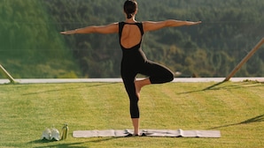 Une personne effectuant une posture de yoga sur un tapis, dans un cadre extérieur avec une chaîne de montagnes en arrière-plan.