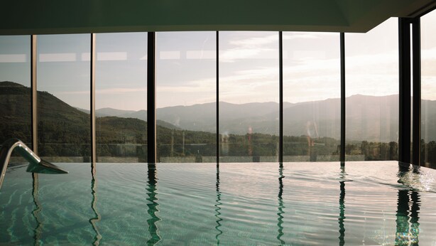 Une piscine à débordement offrant une vue sur les collines et les montagnes lointaines.