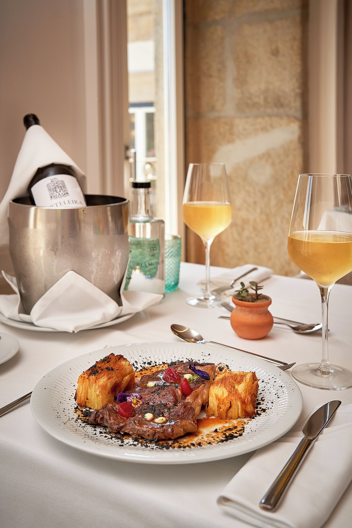 Una mesa de comedor con un plato de comida, dos copas de vino y una botella de champán.