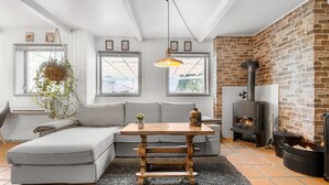 A cozy living room with a grey sectional sofa, a wooden coffee table, and a brick fireplace. - 3 bedroom beautiful home in Grevinge (Grevinge)