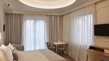 Una habitación de hotel con una cama grande, un escritorio, una silla y un televisor.