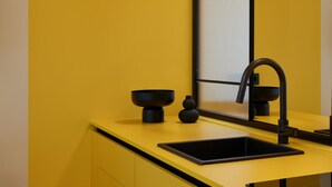 Une cuisine moderne avec un plan de travail jaune, un évier noir et un robinet noir assorti.