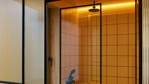Une salle de bain moderne avec un espace douche, des murs carrelés et un panneau en bois sur un des murs.