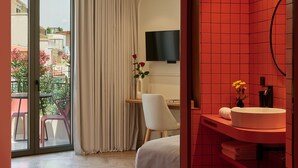 Une chambre d’hôtel moderne dotée d’un balcon, d’un lit, d’un bureau et d’une salle de bain dont les murs sont recouverts de carreaux rouges.