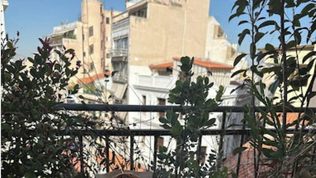 Un plateau de petit-déjeuner sur un balcon, avec du café, des toasts, des œufs et des viennoiseries.