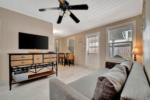 A living room with a flat-screen TV, a ceiling fan, a dining area with a table and chairs, and a sofa.