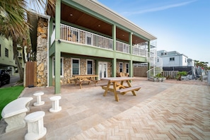 Un bâtiment à la façade en pierre, doté de tables de pique-nique en bois et d’un patio couvert.