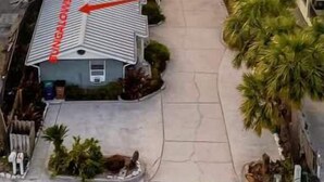 Un edificio de estilo bungalow con techo inclinado, un camino cubierto y vista a la playa.