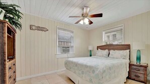 Un dormitorio con cama, mesita de noche, cómoda y ventilador de techo.