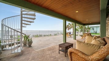 A covered outdoor area with a spiral staircase, wicker furniture, and a view of the ocean.