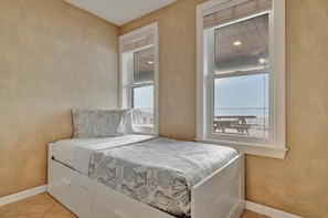 A bedroom with a bed, a window with a view, and a small bedside table.