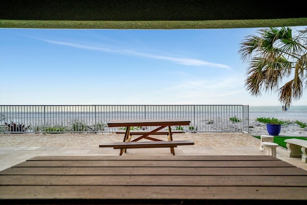 A wooden deck with a picnic table overlooking a beach.