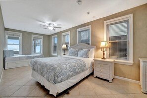 Een slaapkamer met een bed, nachtkastjes, een lamp en een vensterbank.