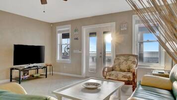 Relax in your bright living room where French doors open onto a balcony with ocean views. Soft coastal breezes, comfortable seating, and that serene waterfront vista create the perfect escape.
