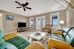 Step into your bright living area with coastal-inspired décor and let natural light pour in through windows and French doors. Relax on comfy seating while enjoying your ocean view balcony access.