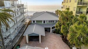 A multi-story building with a covered parking area and a view of the beach.