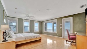 A spacious bedroom with a bed, a desk, a chair, and a large window offering a view. - Relax on the Beach! Private Balcony Oceanview (Indian Rocks Beach)
