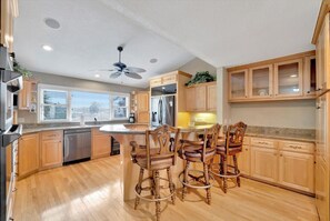 Gather around the spacious island in this fully-equipped kitchen with modern appliances and plenty of natural light streaming through large windows. Wood cabinetry and generous counter space make meal prep a breeze during your stay.