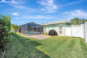 The property features a screened pool area and well-maintained lawn, bordered by lush tropical landscaping and a white privacy fence—perfect for enjoying sunny Florida days. - BBQ & Pool Day! Large 4B 12 minutes to the Beach! (Largo)