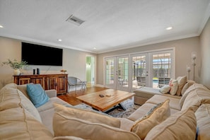 A living room with a large flat-screen TV, a wooden coffee table, and a sofa. - BBQ & Pool Day! Large 4B 12 minutes to the Beach! (Largo)