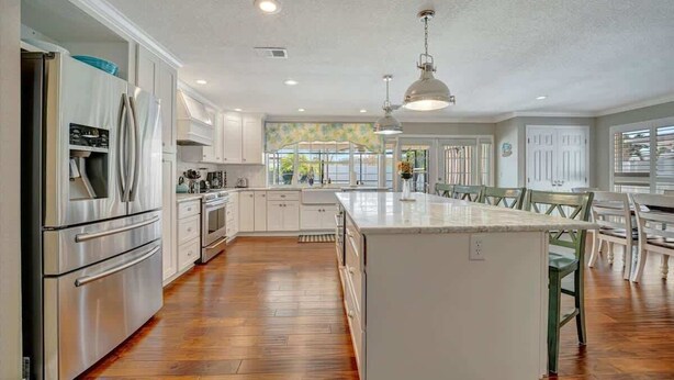 A spacious kitchen with white cabinets, stainless steel appliances, and a large island.