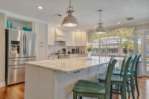 A kitchen with a central island, stainless steel appliances, and a view to the outside. - BBQ & Pool Day! Large 4B 12 minutes to the Beach! (Largo)