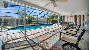 A pool area with a glass enclosure, outdoor seating, and a ceiling fan.
