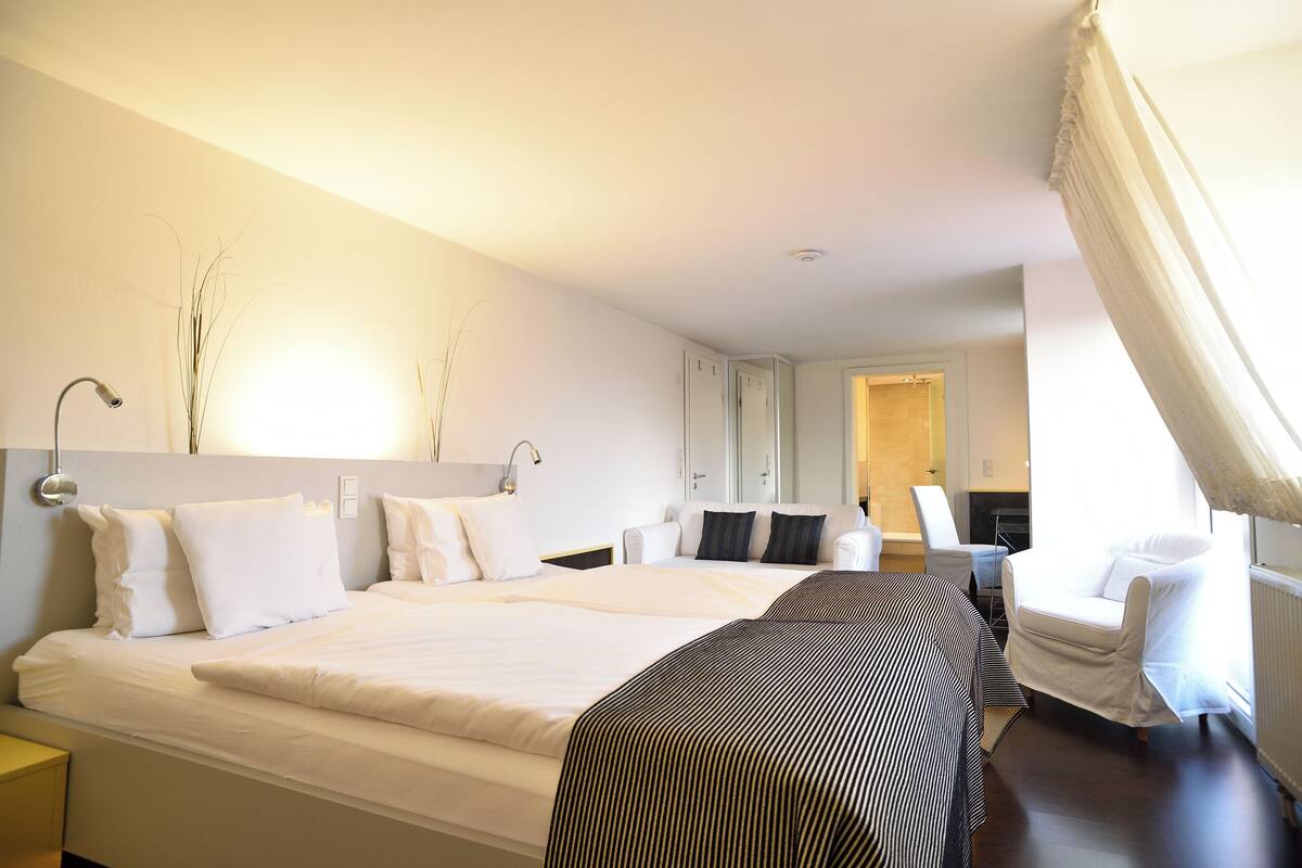 A hotel room with a large bed, a chair, and a desk.