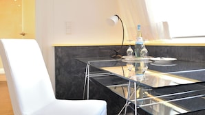 A modern dining area with a glass table, a white chair, and a bottle of water.