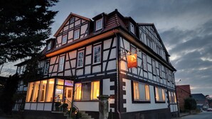 A traditional half-timbered building with a well-lit entrance and a visible staircase leading to the door.