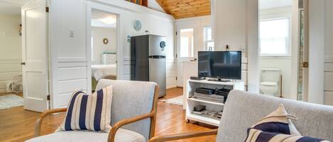 A spacious living room with a high ceiling, wooden beams, and a built-in entertainment unit.