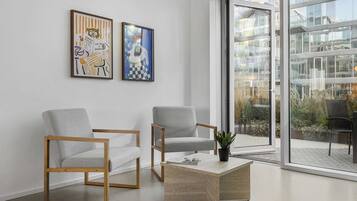 Ein modernes Interieur mit zwei grauen Sesseln, einem Holztisch und zwei gerahmten Kunstwerken an der Wand.