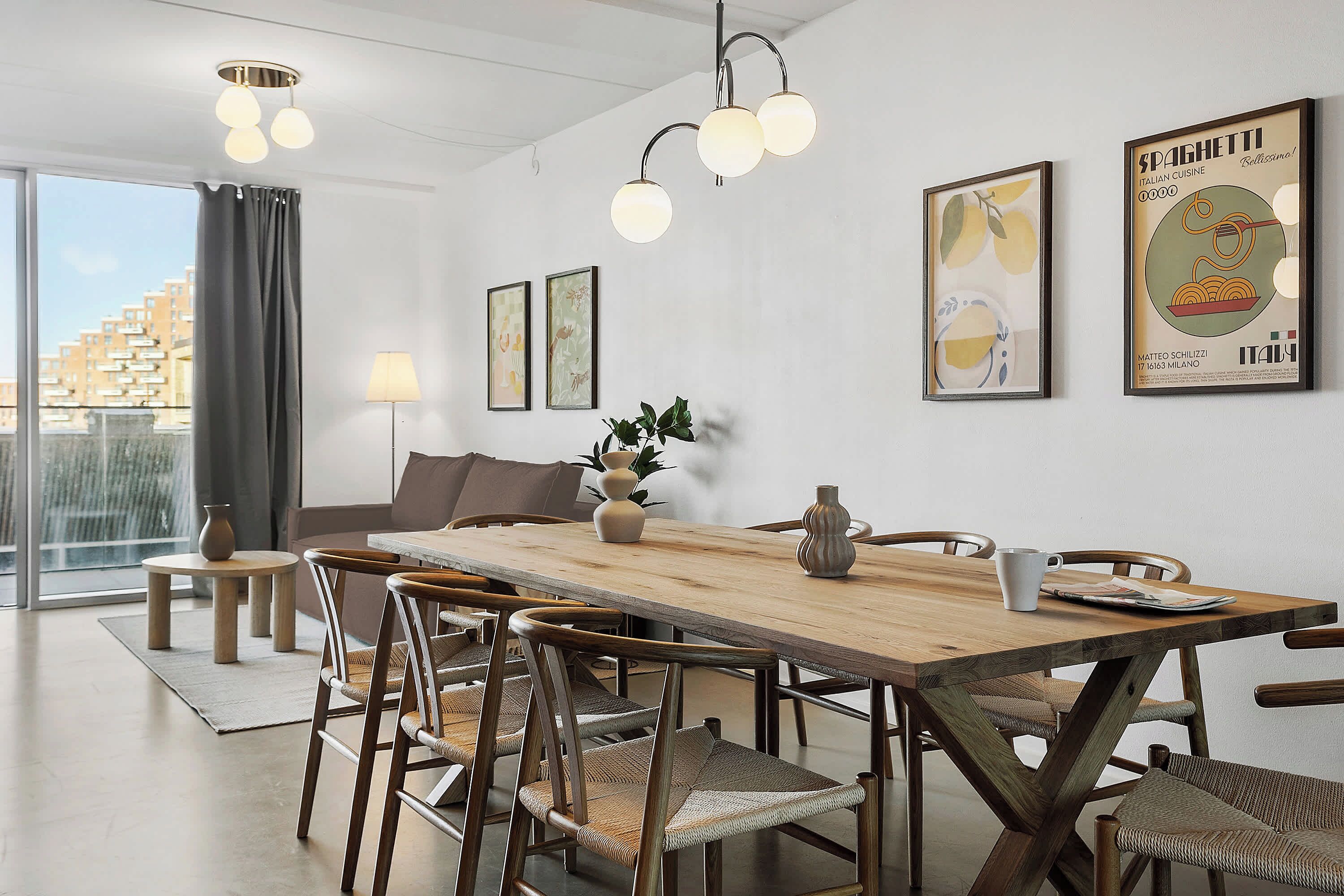 Ein Essbereich mit einem Holztisch, Stühlen und einer Hängelampe. An der Wand befinden sich gerahmte Bilder und ein Fenster mit Vorhängen.