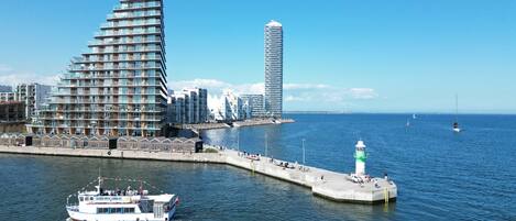 A waterfront cityscape with modern architecture, a pier, and a boat.