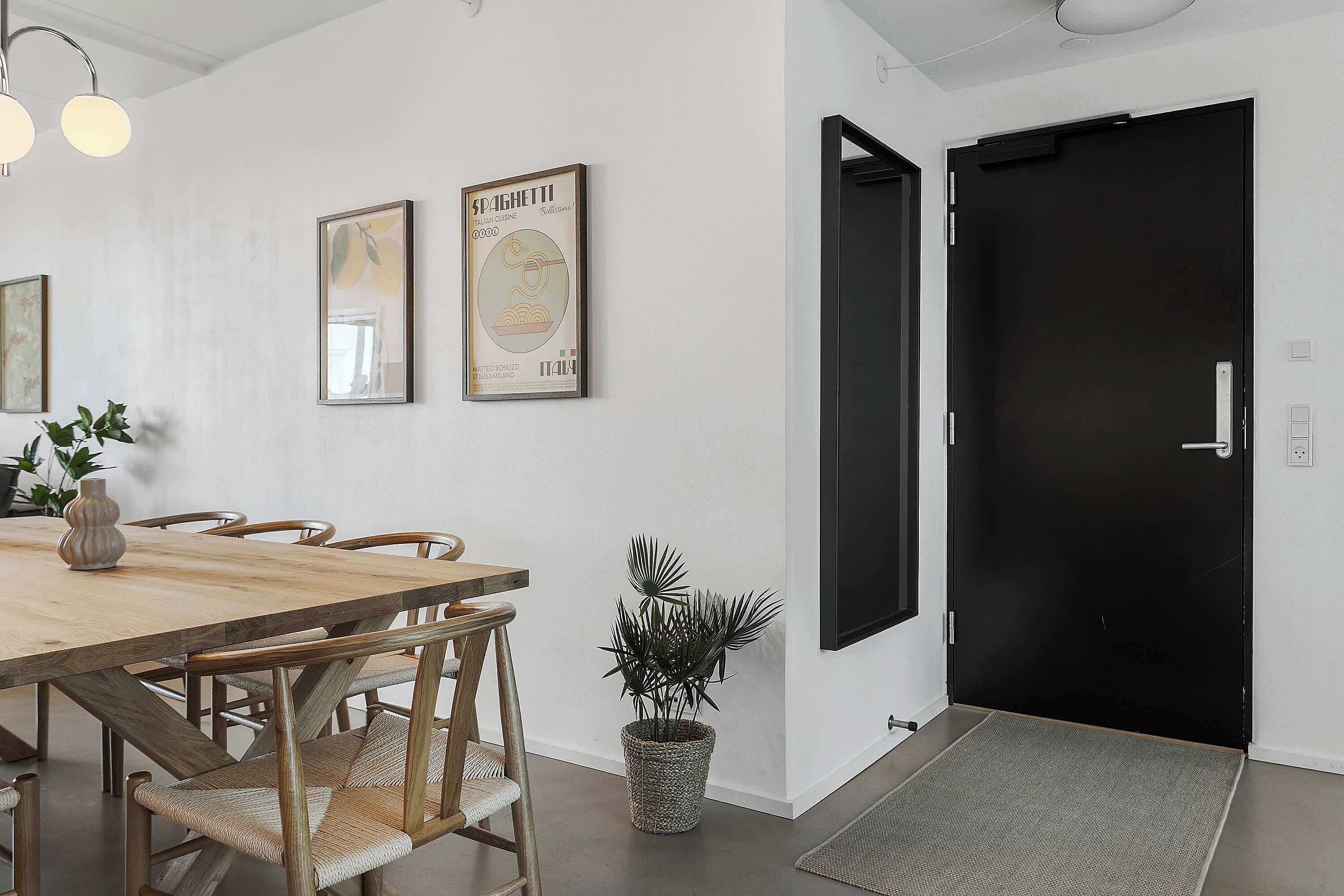 Un coin repas avec une table en bois, des chaises, une plante en pot et des tableaux encadrés au mur.