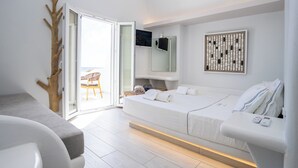 A modern bedroom with a bed, bedside table, and a view of the balcony. - Zen Suites & Spa (Santorini)