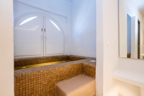 A bathroom with a white cabinet, a tiled sink, and a mirror. - Zen Suites & Spa (Santorini)