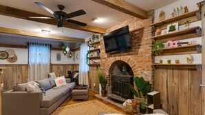 A cozy living room with a fireplace, a sofa, and a TV mounted on the wall.
