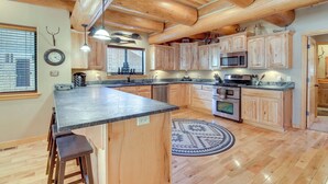 A spacious kitchen with wooden cabinets, a central island, and a built-in microwave. - Fire Pit: Cozy Winter Cabin, 45 Mi to Sunrise Park (Show Low)