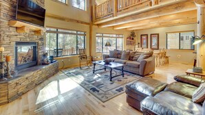 A spacious living room with a fireplace, a large sofa, and a high ceiling with wooden beams. - Fire Pit: Cozy Winter Cabin, 45 Mi to Sunrise Park (Show Low)