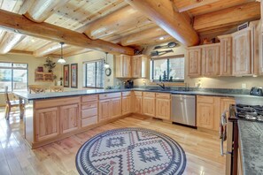 A spacious kitchen with wooden cabinets, a granite countertop, and a central island. - Fire Pit: Cozy Winter Cabin, 45 Mi to Sunrise Park (Show Low)