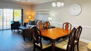 A dining area with a wooden table and chairs, a ceiling fan, and a clock on the wall. - Memorable stay at cozy 2BR condo in Magnolia (Myrtle Beach)