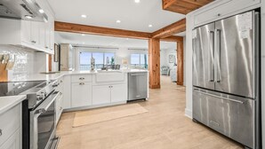 A modern kitchen with white cabinets, stainless steel appliances, and wooden beams. - 632 Newhaven (Fripp Island)