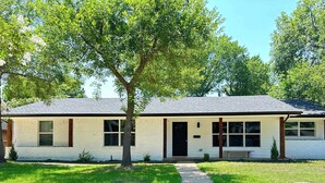 A single-story house with a front porch, a small front yard, and a tree in front.