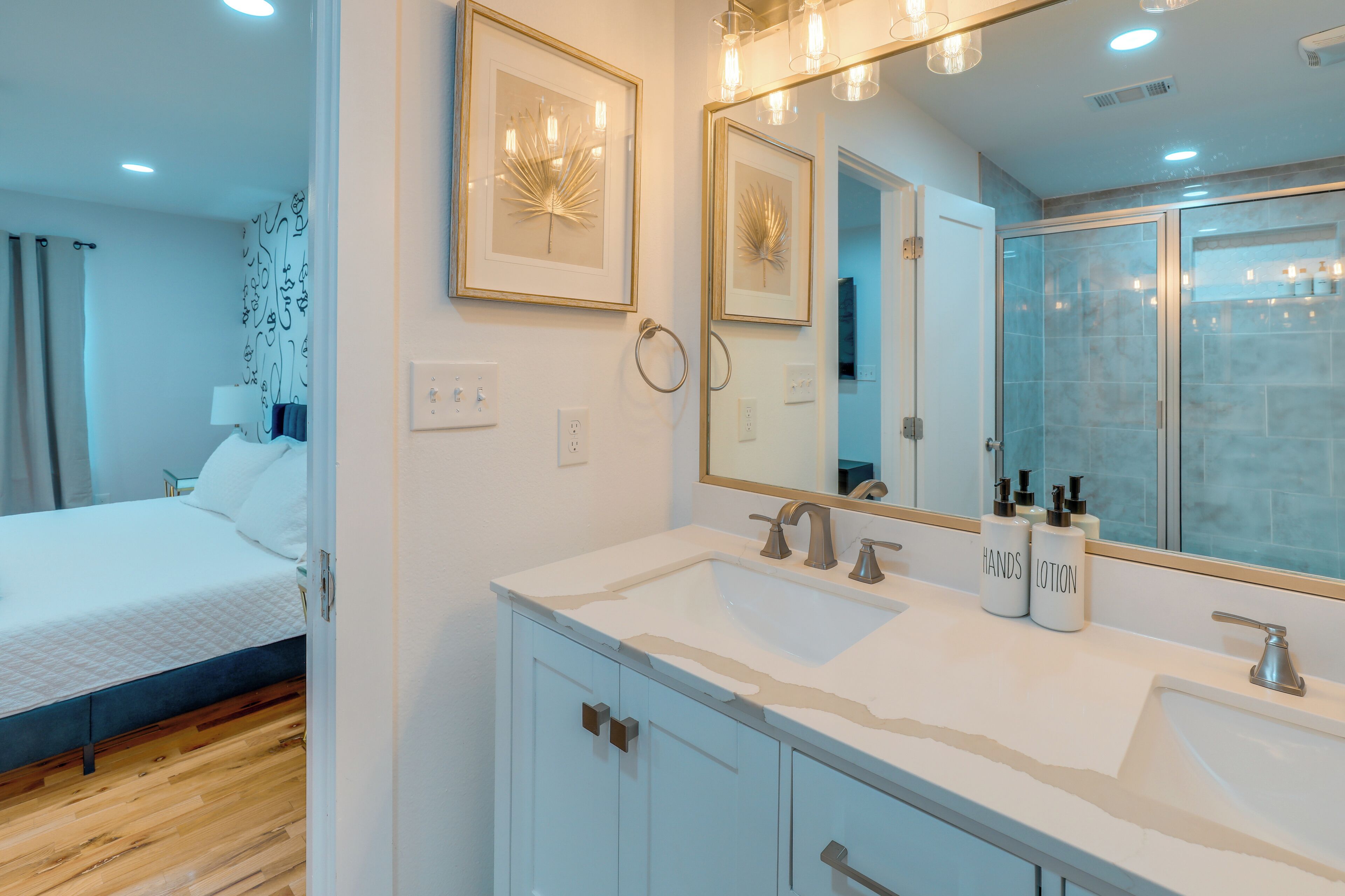 A modern bathroom with a large mirror, two sinks, and a shower.