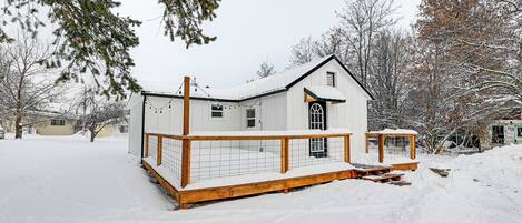 Una casa de dos pisos con un balcón de madera y un tejado cubierto de nieve.