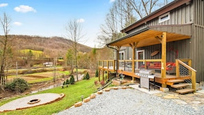 A cabin with a wooden deck, outdoor seating, and a barbecue area.