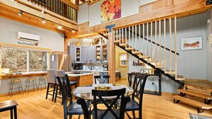 A spacious kitchen with modern appliances, a dining area with a round table and chairs, and a staircase leading to an upper level.