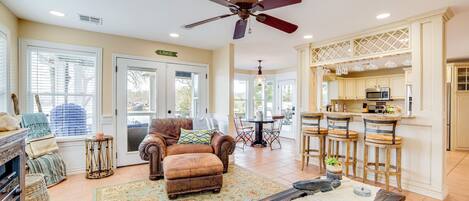 A spacious living room with a fireplace, a dining area, and a kitchen with bar stools.