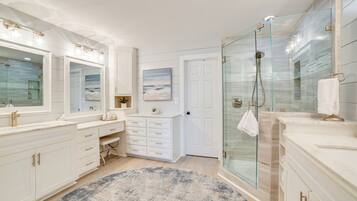 A spacious bathroom with a large vanity, a glass shower enclosure, and a round rug.